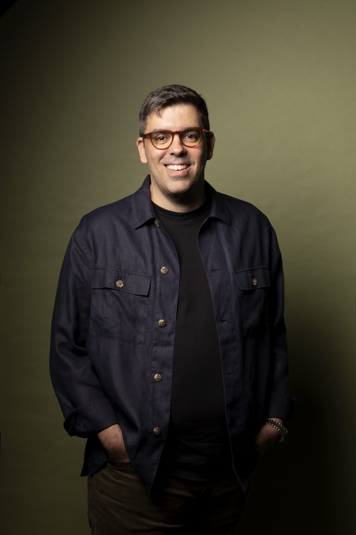 Eduardo Cruz em pé, sorrindo, de camisa de linho azul-marinho